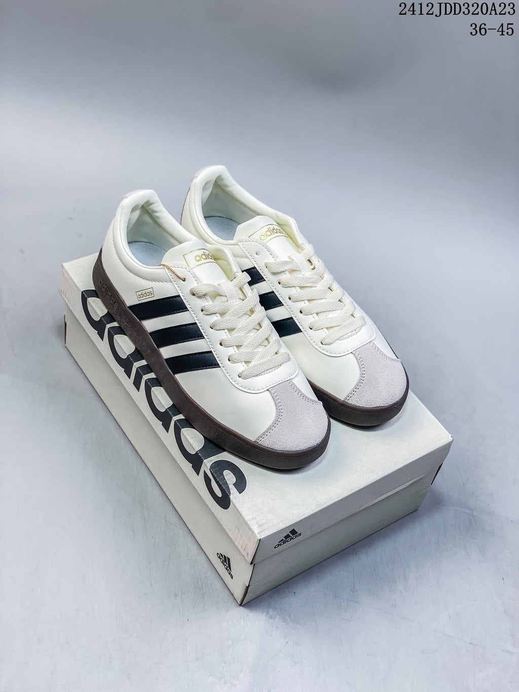 White Adidas VL Court Classic sneakers with navy stripes and a dark brown sole, shown on a shoebox