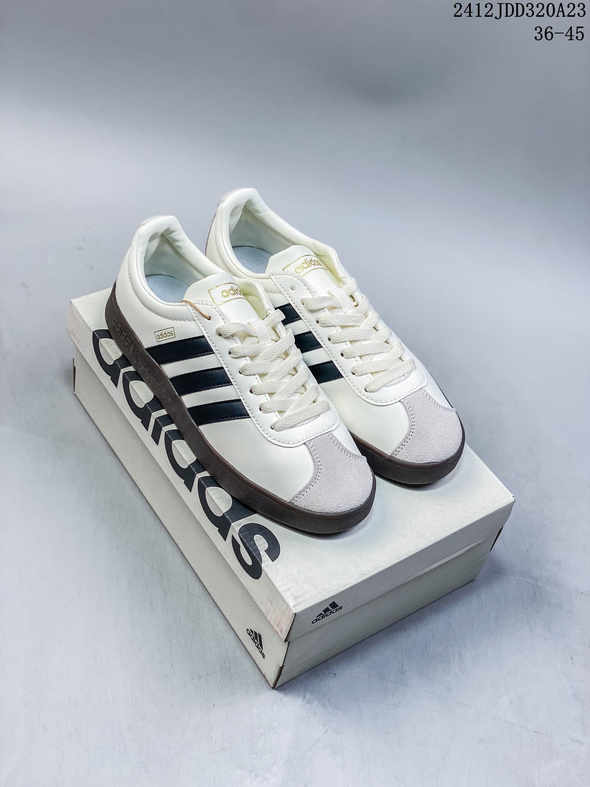 White Adidas VL Court Classic sneakers with navy stripes and a dark brown sole, shown on a shoebox