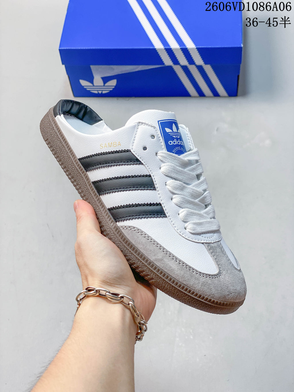 Close-up of a white and gray Samba-style sneaker with dark side stripes and a gum-colored outsole.