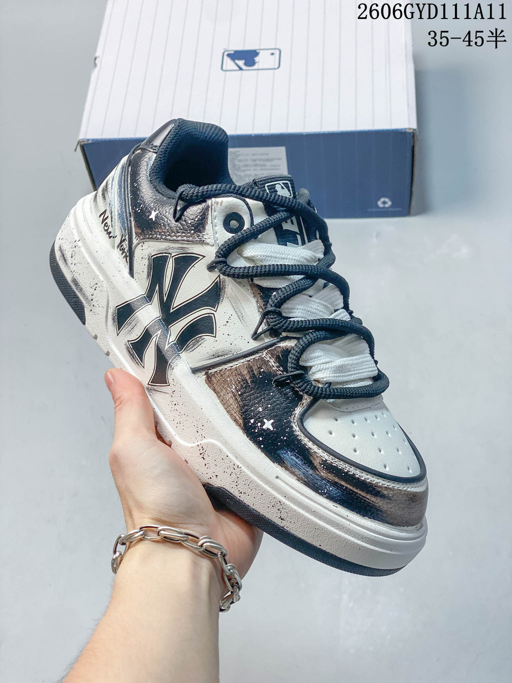 Angled side view of the white and navy sneaker with a large side logo and contrasting laces.