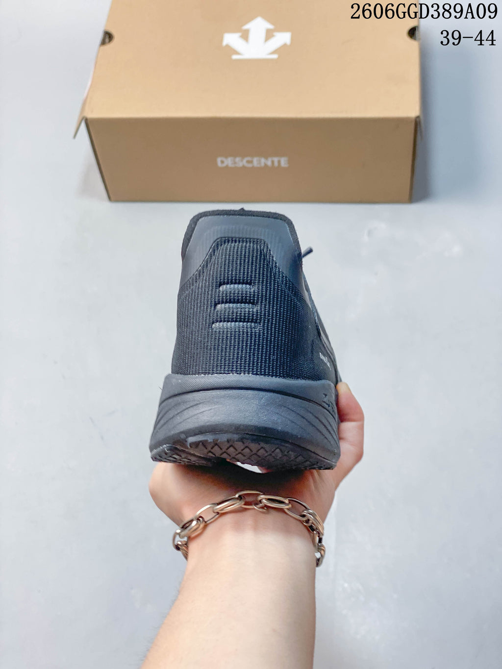 Rear view showing the heel and thick sole of a dark gray Descente running shoe.