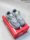 Grey Nike Air Max 90 sneakers with white laces and yellow accents, shown on a red shoe box.