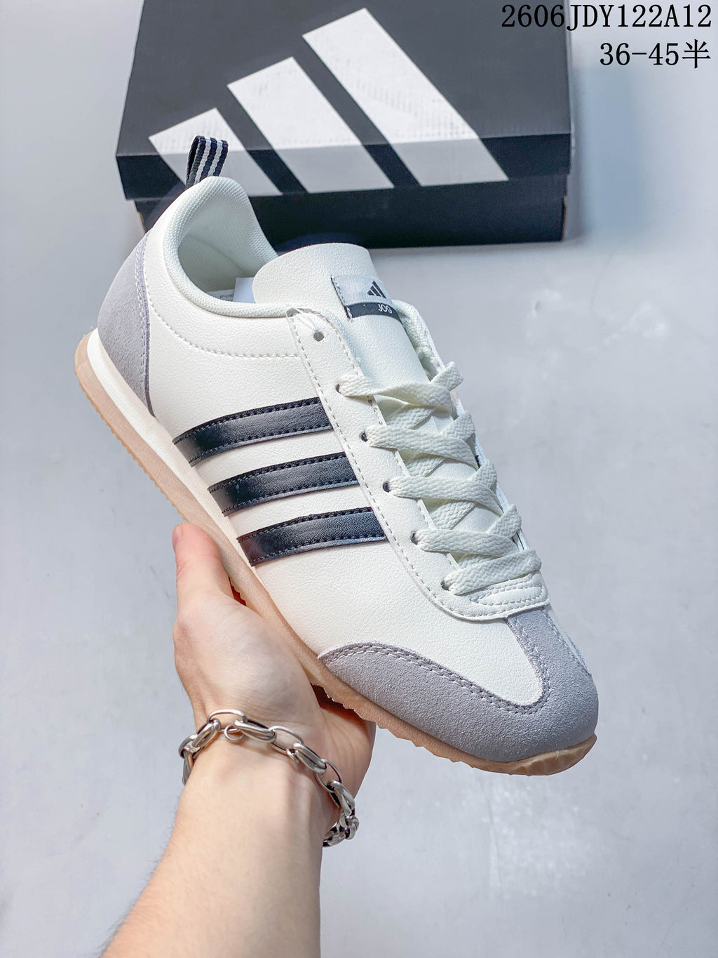 Side view of a cream Adidas Originals VS JOG 2.0 sneaker with dark stripes and gray toe accents