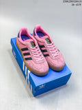 Pair of pink Adidas Gazelle 90 low-top sneakers with dark stripes and gum-look soles, shown on a blue shoe box.