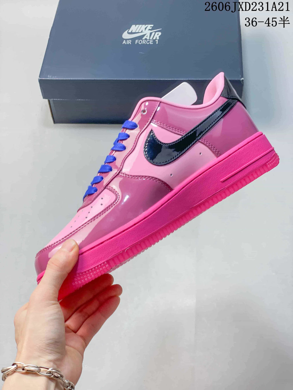 Side view of a pink Nike Air Force 1 sneaker with glossy dark Swoosh and blue laces