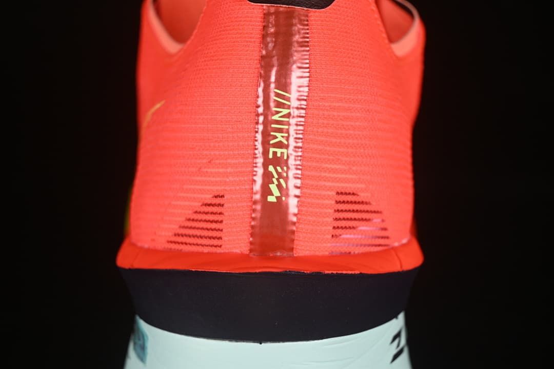 Rear view highlighting the coral upper, center heel strip and contrasting midsole.