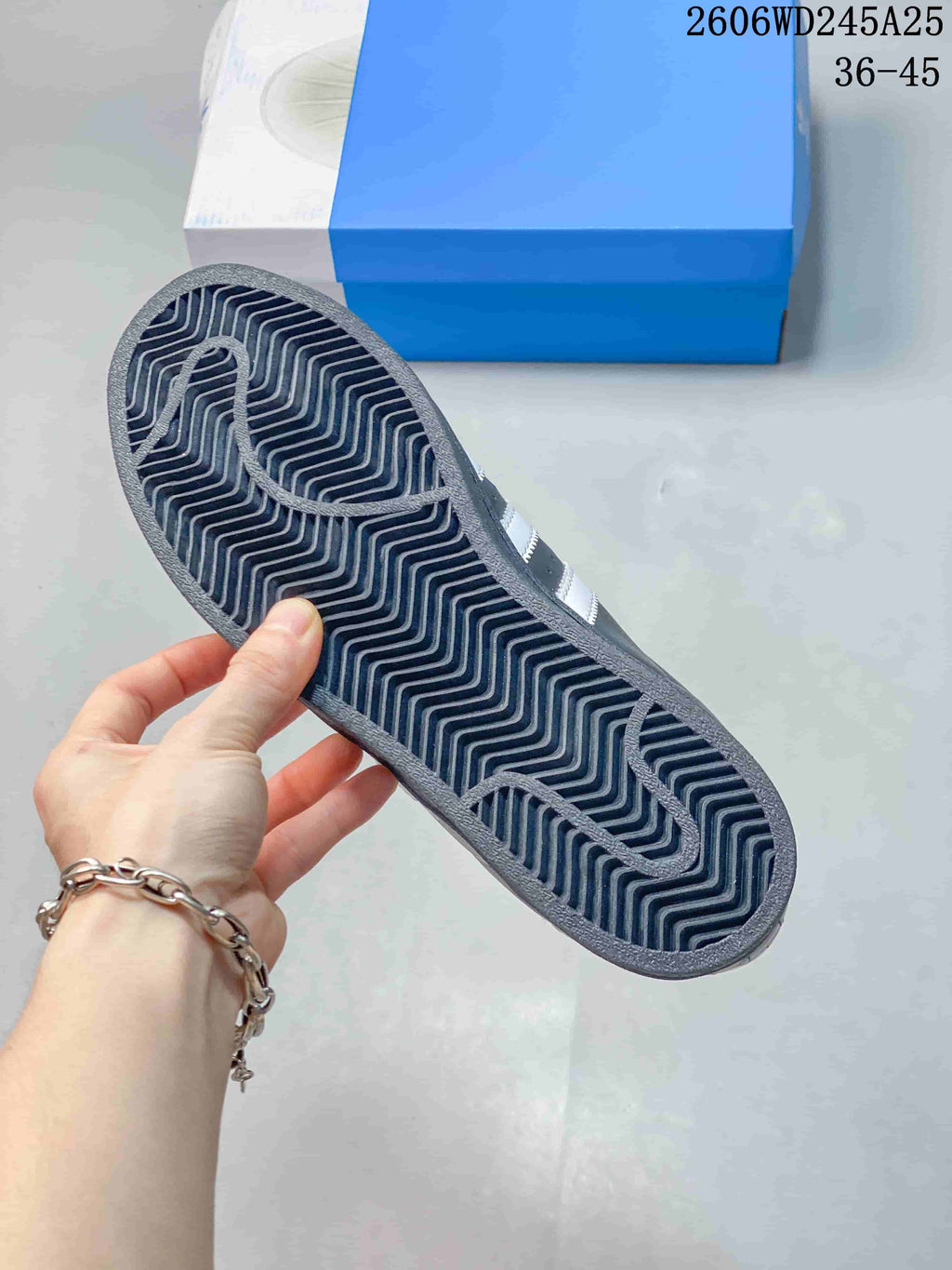 Underside of a charcoal sneaker showing a patterned tread