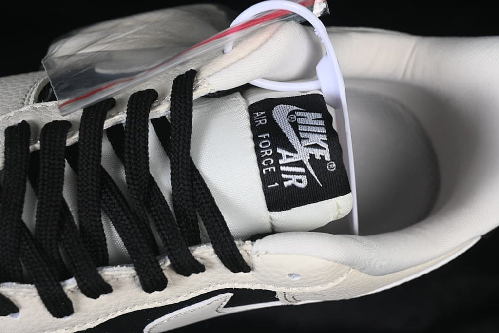 Close-up of the Nike Air Force 1 tongue, black laces, and sail-colored upper