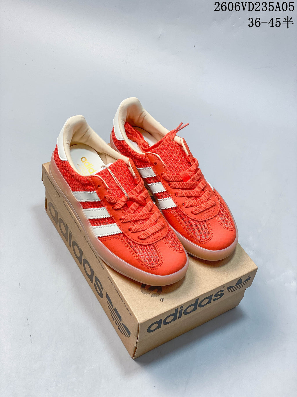 Red Adidas Samba sneakers with white stripes, shown with a shoe box