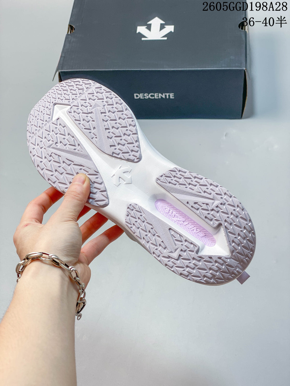 Outsole view of white and pale lavender DESCENTE running shoes.