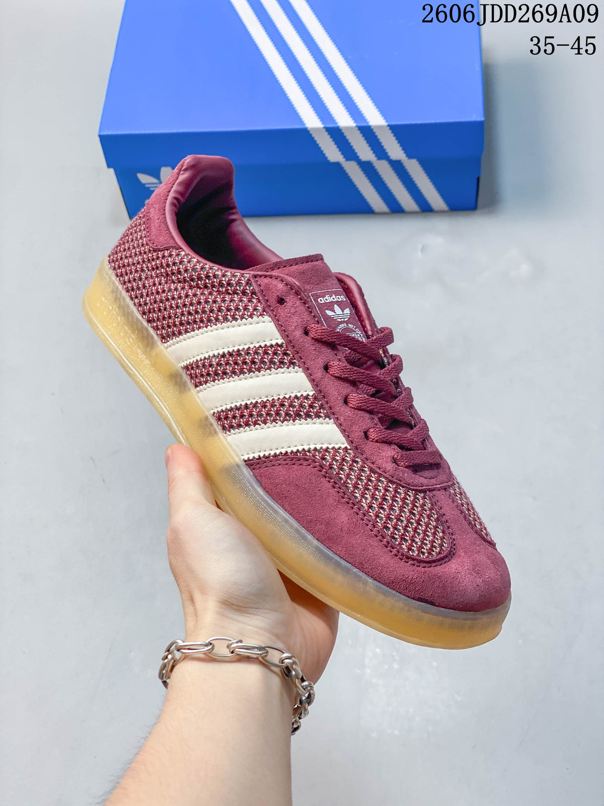 Side view of a burgundy adidas Gazelle Indoor sneaker with light stripes and a gum-colored outsole
