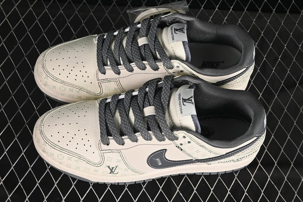 Overhead view of a pair of cream and gray low-top sneakers with dark laces and monogram patterning.