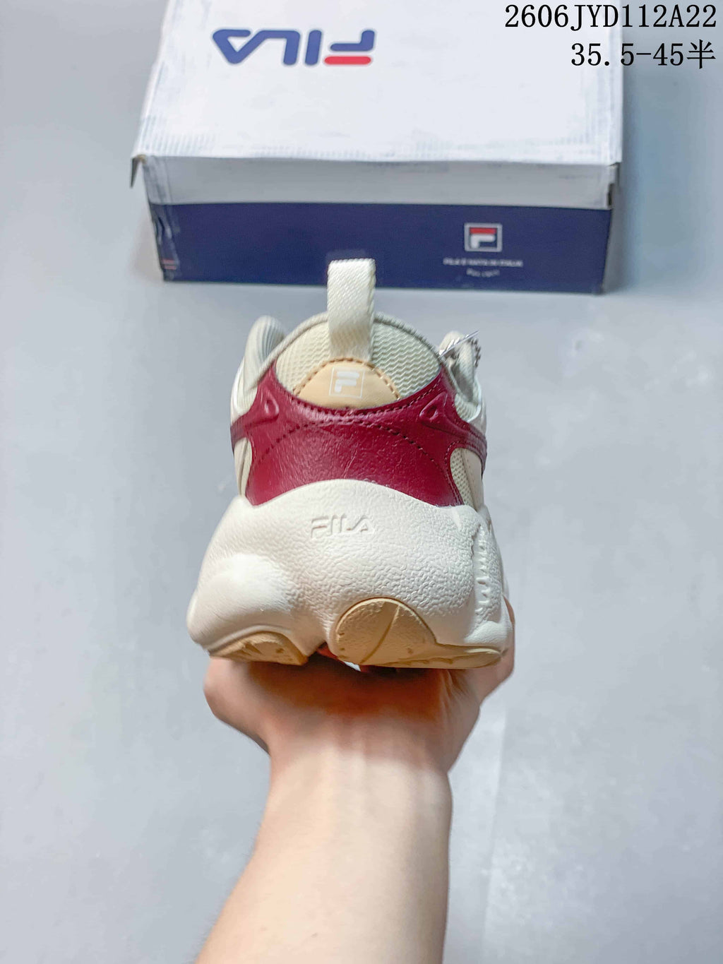 Rear view of the sneaker showing burgundy heel detailing and a chunky cream sole.