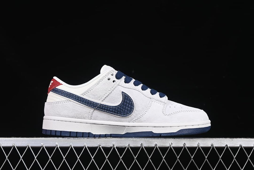 Side profile of the white low-top sneaker with a navy patterned swoosh