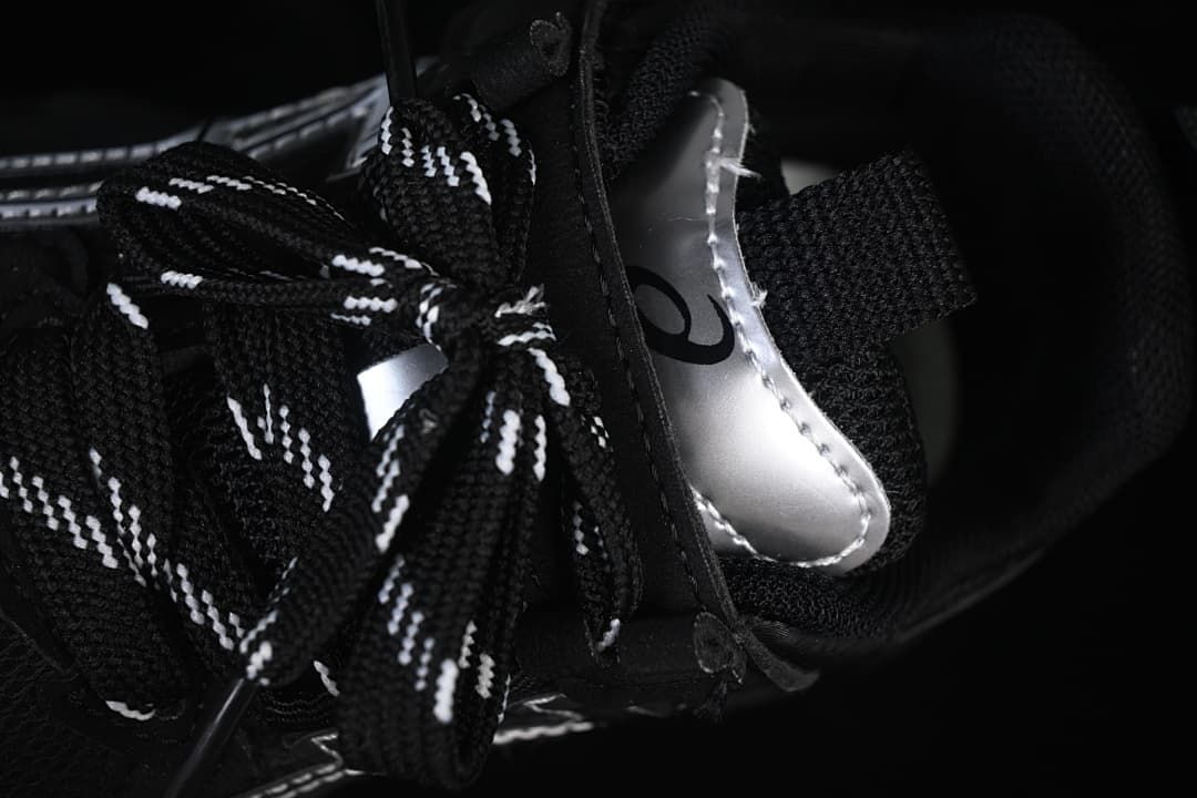 Close-up of the patterned black-and-white laces and silver tongue detail.