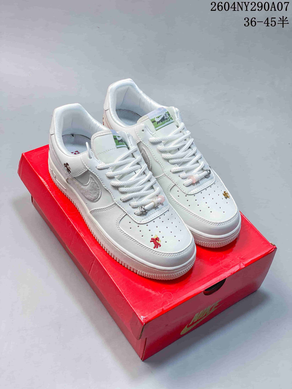Pair of white low-top sneakers with small embroidered motifs and metallic accents.