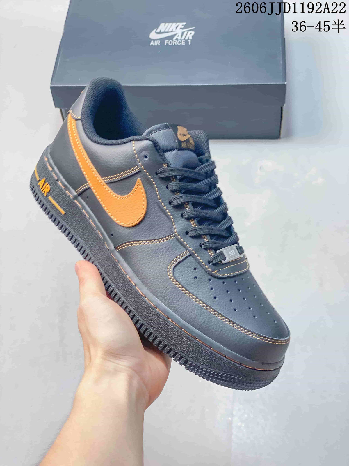 Close-up of a charcoal gray low-top sneaker with orange accents and perforated toe