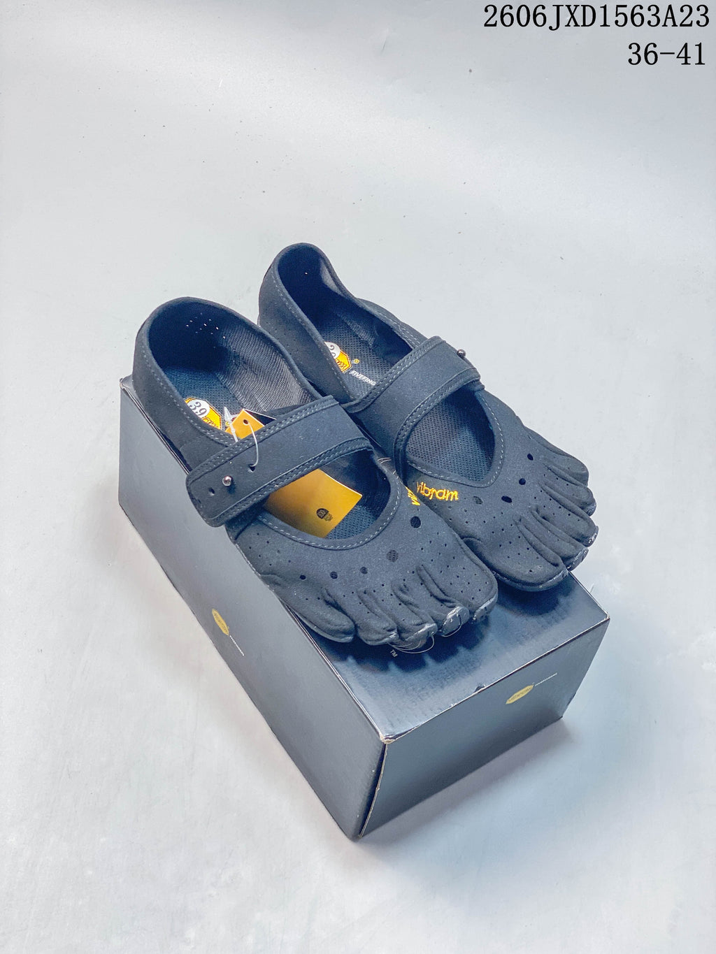 Pair of gray FiveFingers-style shoes with individual toe compartments and adjustable straps, displayed on a box