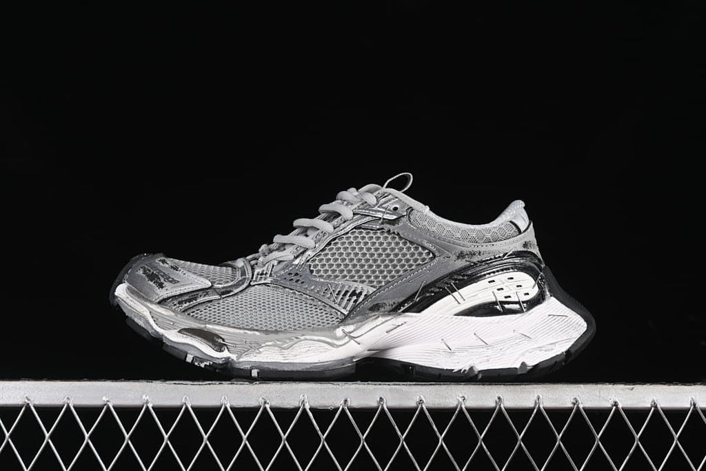 Side view of a grey and silver chunky sneaker against a black background
