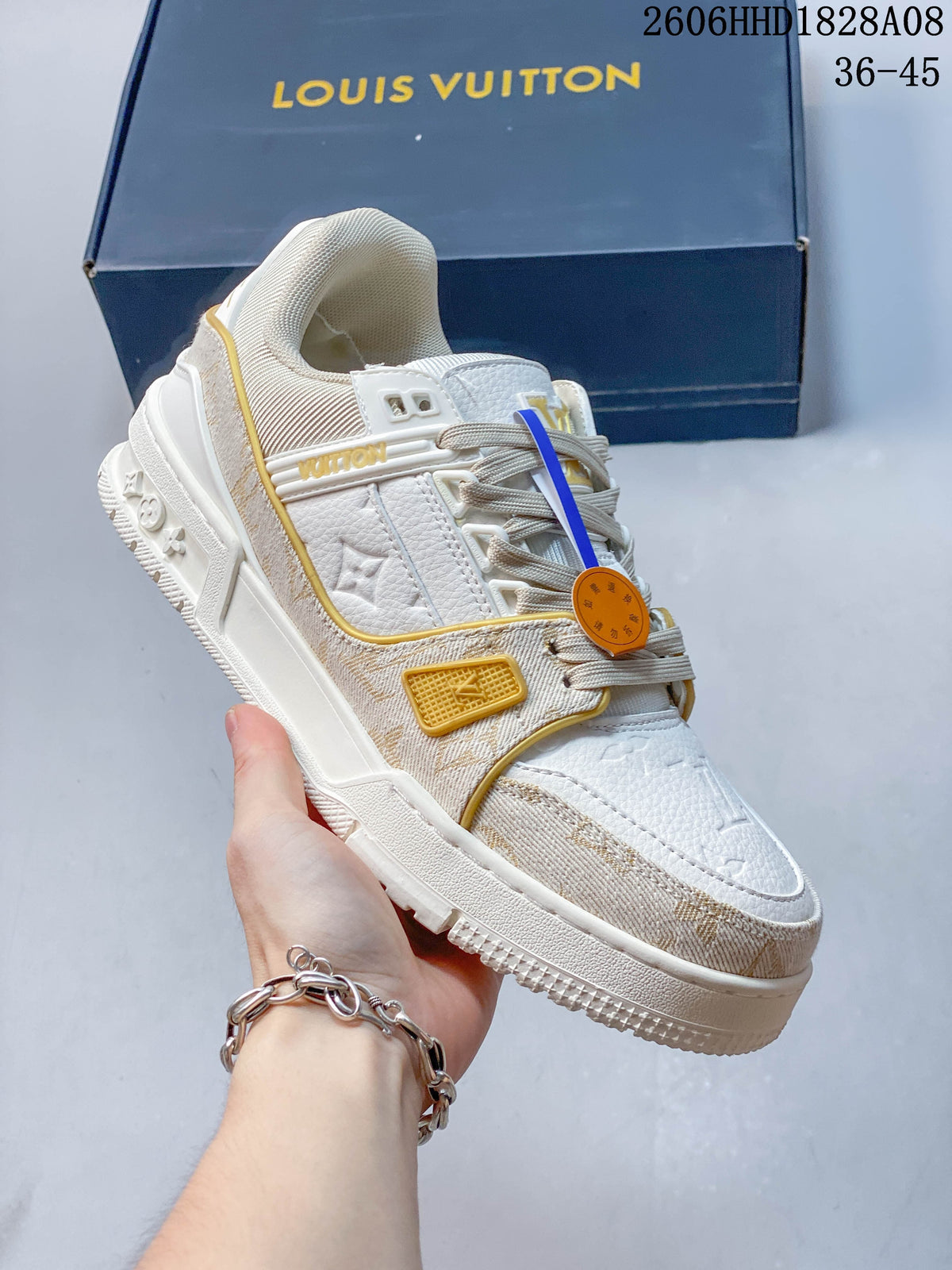 Angled view of a white and beige low-top sneaker with patterned trim and a sculpted sole.