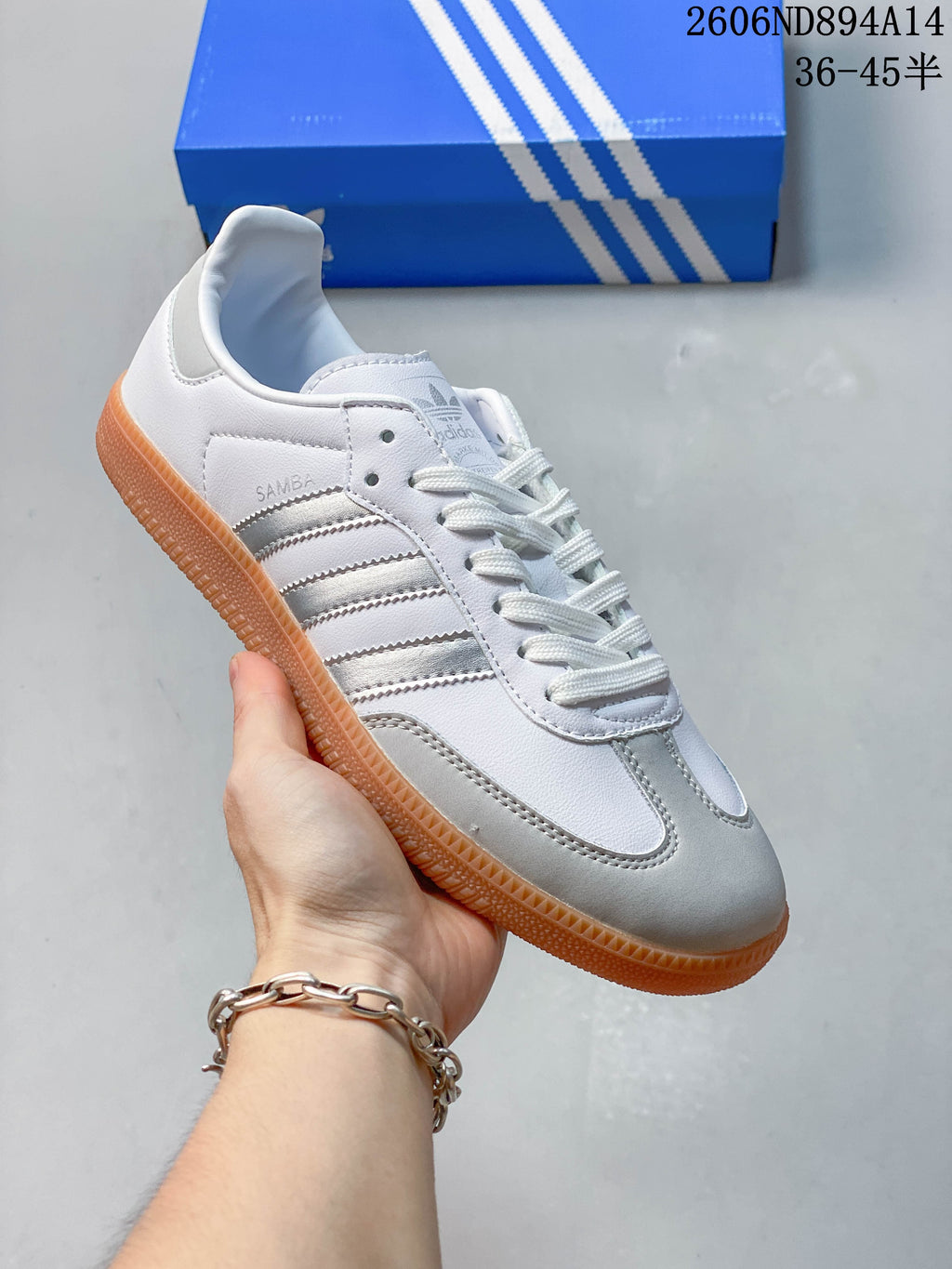 Angled side view of a white adidas Samba OG sneaker with silver stripes and a gum-colored outsole