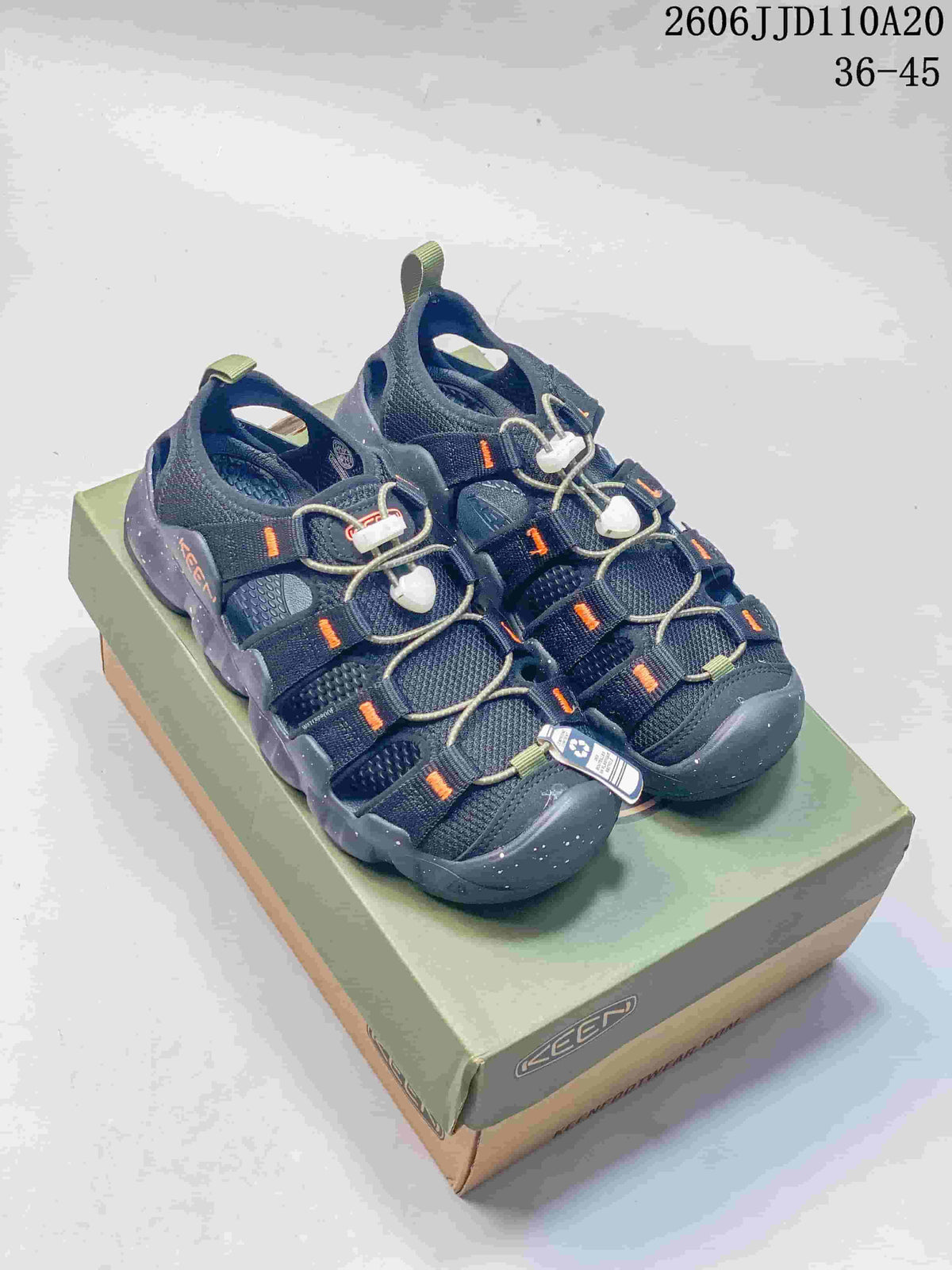 Pair of dark navy KEEN Newport H2 sandals with orange accents on a shoebox.