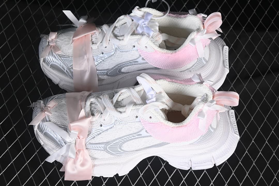 Pair of white sneakers with silver-toned details, pink collar trim, and ribbons.