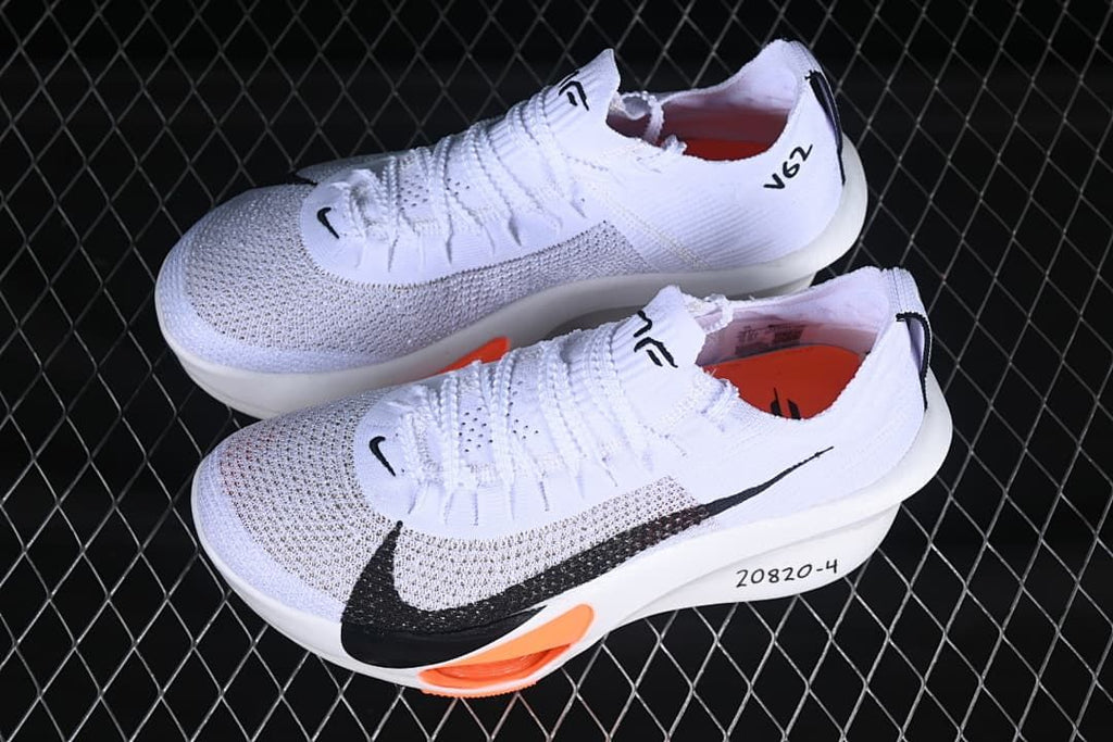 Pair of white running shoes with black Swoosh detailing and orange accents