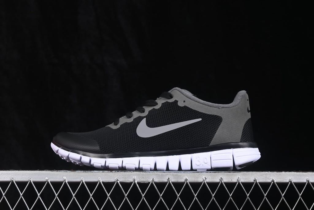 Side profile of black and grey Nike Free 3.0 sneakers with a white segmented outsole.