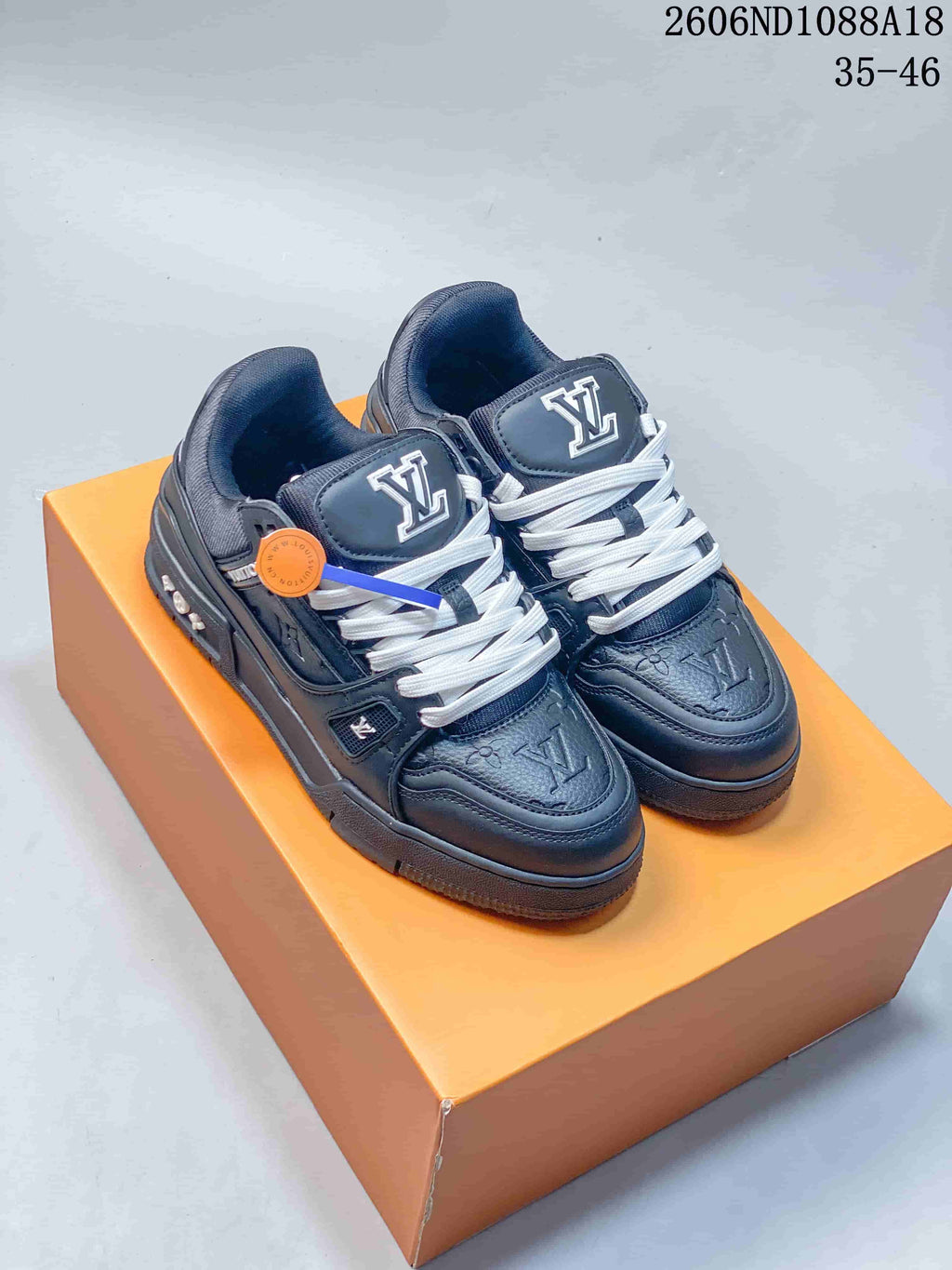 Pair of dark navy Louis Vuitton Trainer low-top sneakers with white laces, photographed on an orange box