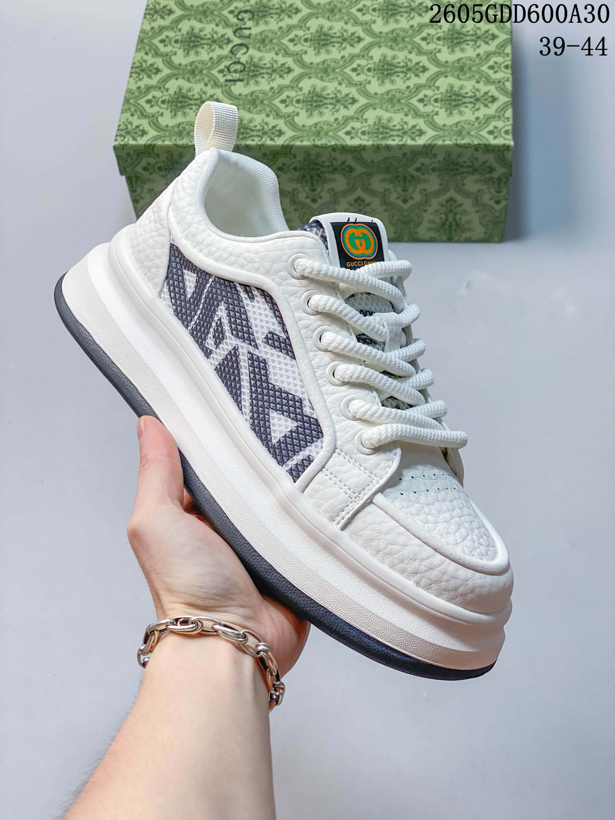 Angled side view of the white sneaker with dark patterned side panels.