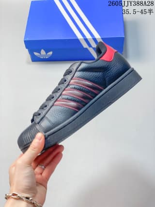 Side view of a dark adidas Originals Superstar 2 sneaker with red accents