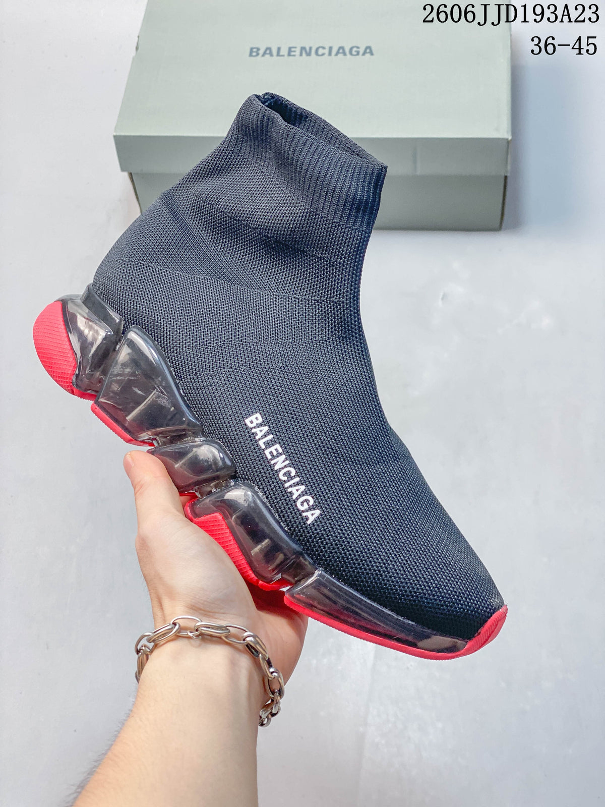 A navy Balenciaga sock-style sneaker with red sole accents, shown from the side.