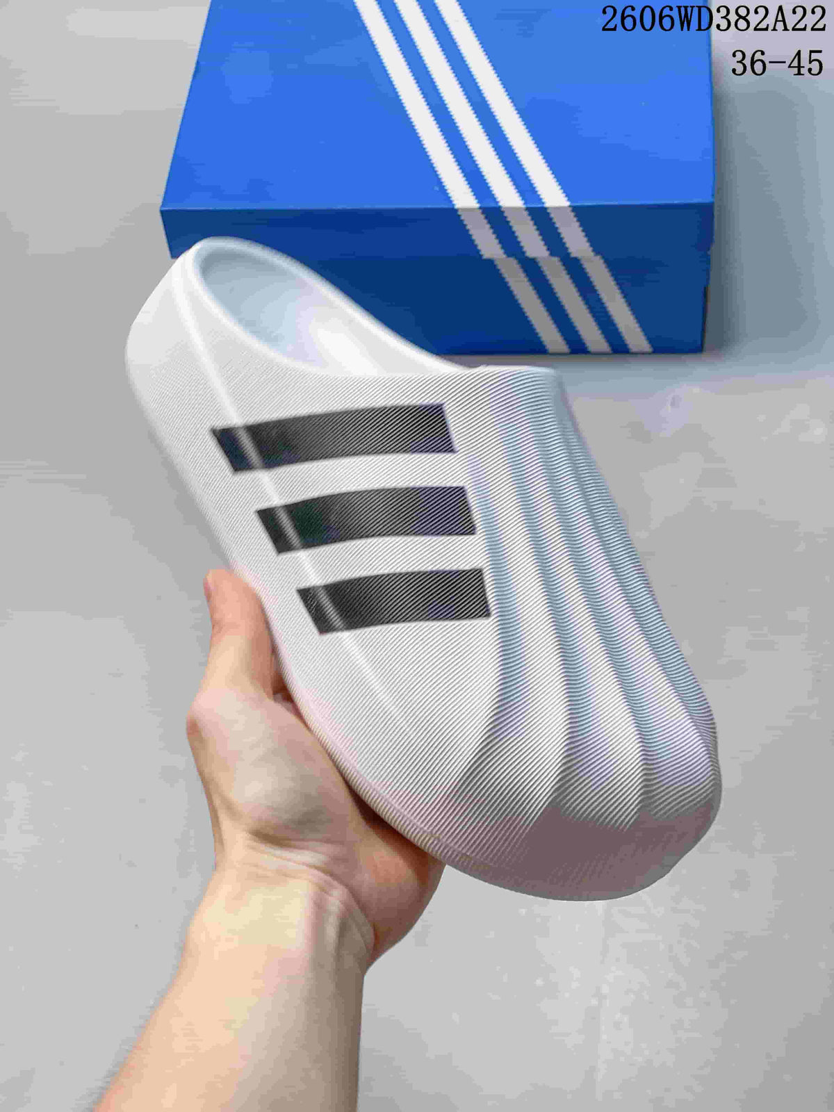 Close angled view of a white closed-toe slide with three black stripes