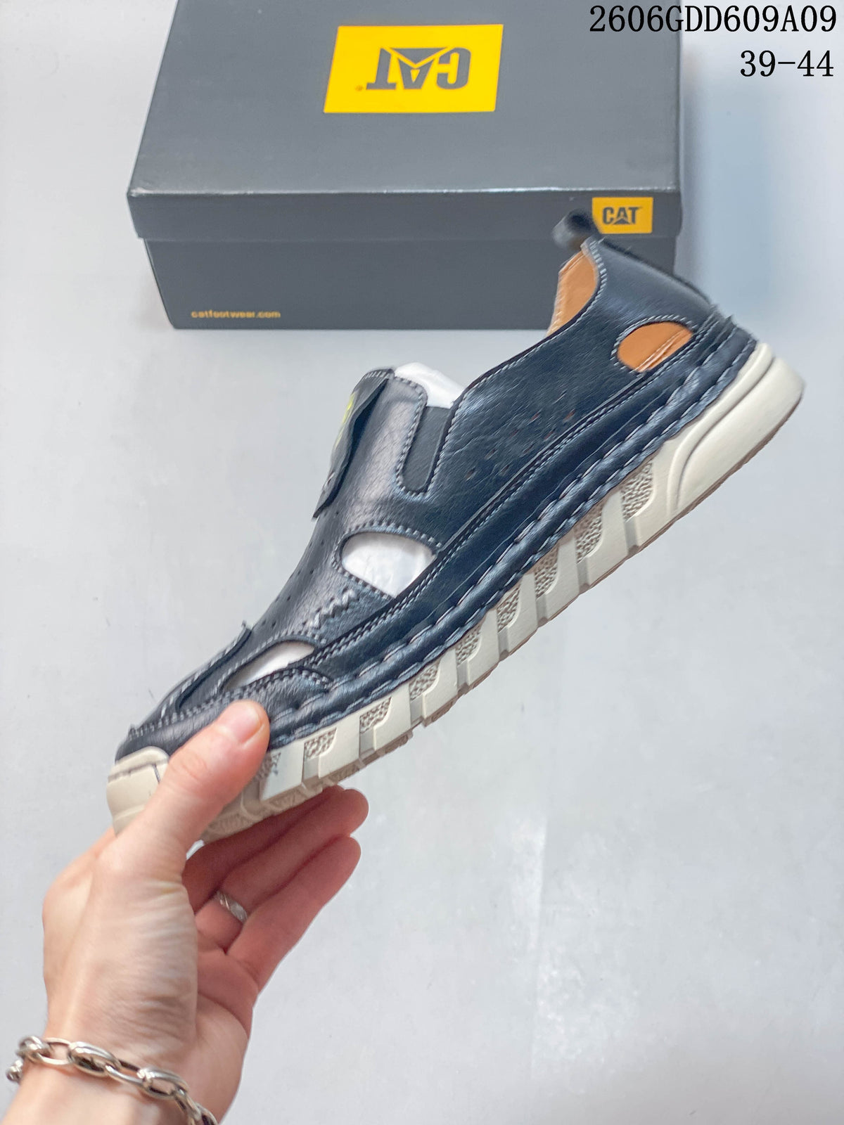Side view of a navy fisherman sandal with open cutouts, contrast stitching, and a lugged light-colored sole; image overlay shows sizes 39–44.