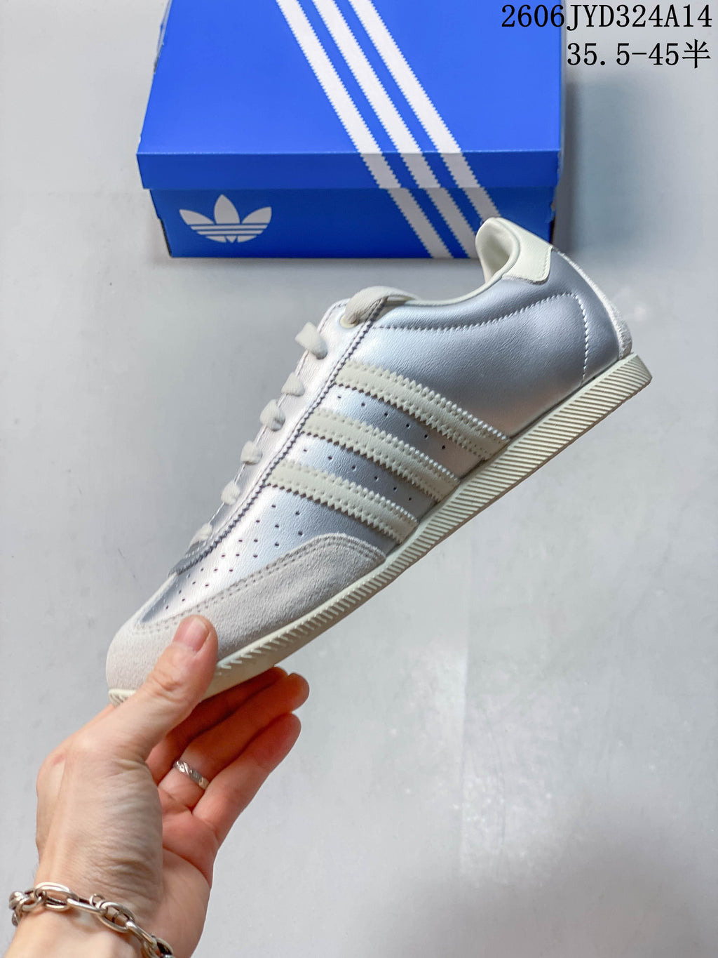 Side profile of a silver Adidas CHANGLE sneaker with off-white stripes and accents