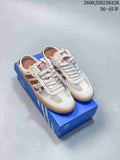 Cream and brown Adidas Samba-style low-top mule sneakers with mesh panels and gum-colored soles on a blue box