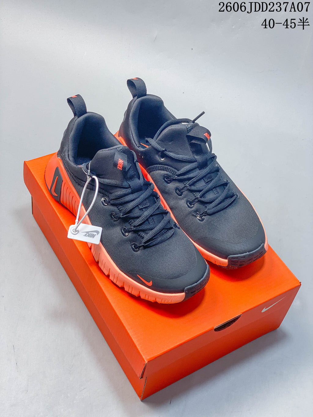 Pair of dark Nike Free Metcon 6 shoes with orange accents displayed on an orange shoe box
