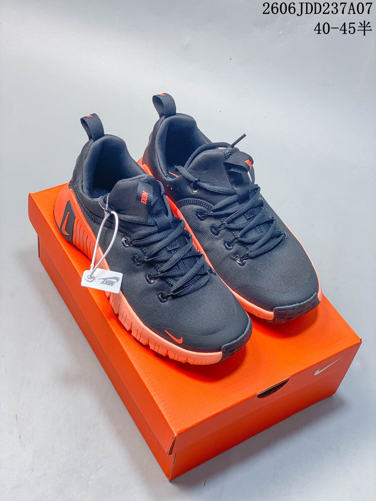Pair of dark Nike Free Metcon 6 shoes with orange accents displayed on an orange shoe box