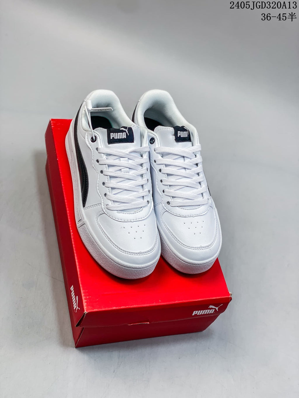 Pair of white PUMA low-top sneakers with black side stripes on a red shoebox