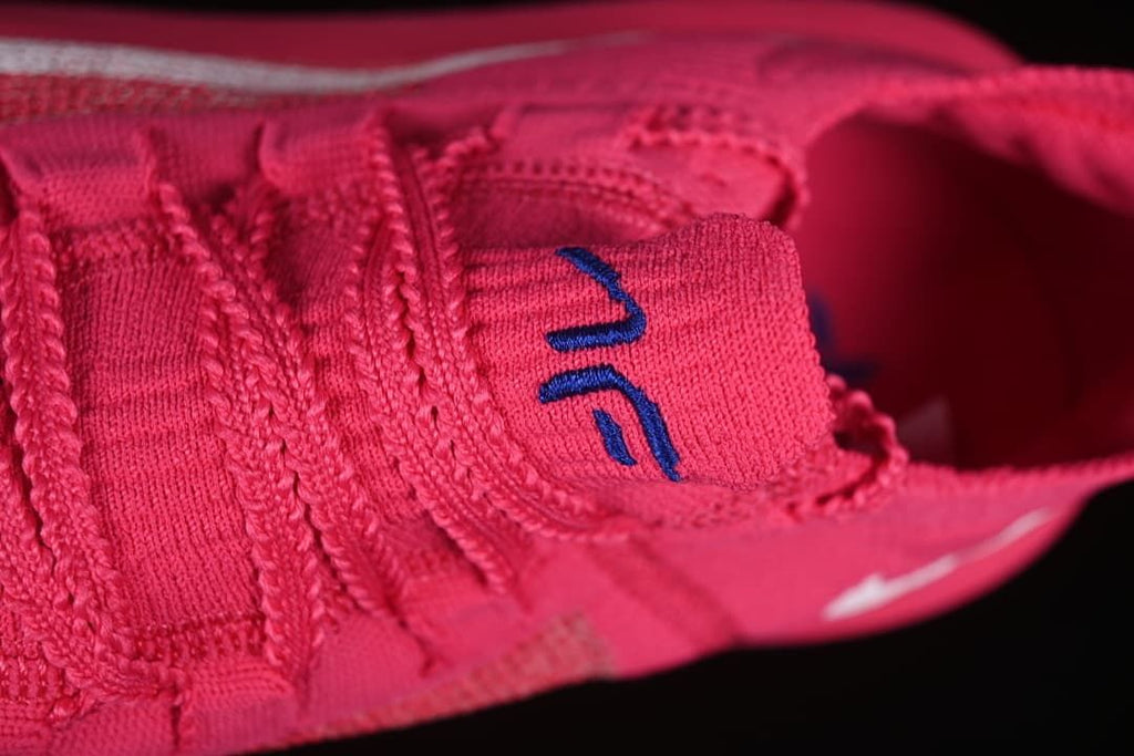 Close-up of the pink tongue and lace area with a blue logo.