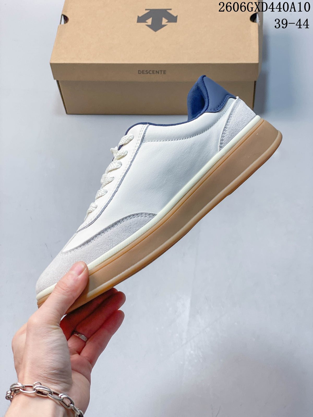 Side view of the white sneaker with gray suede-look panels, navy heel accent, and gum-colored sole.