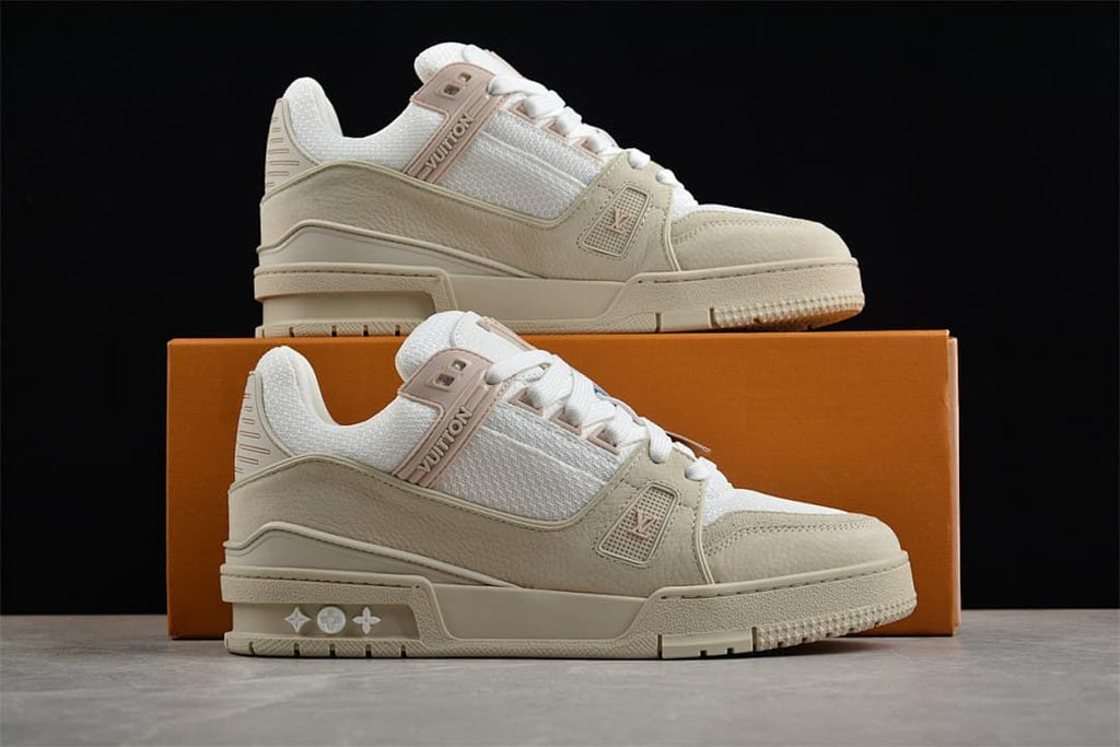 Pair of beige and white sneakers displayed with an orange shoebox.