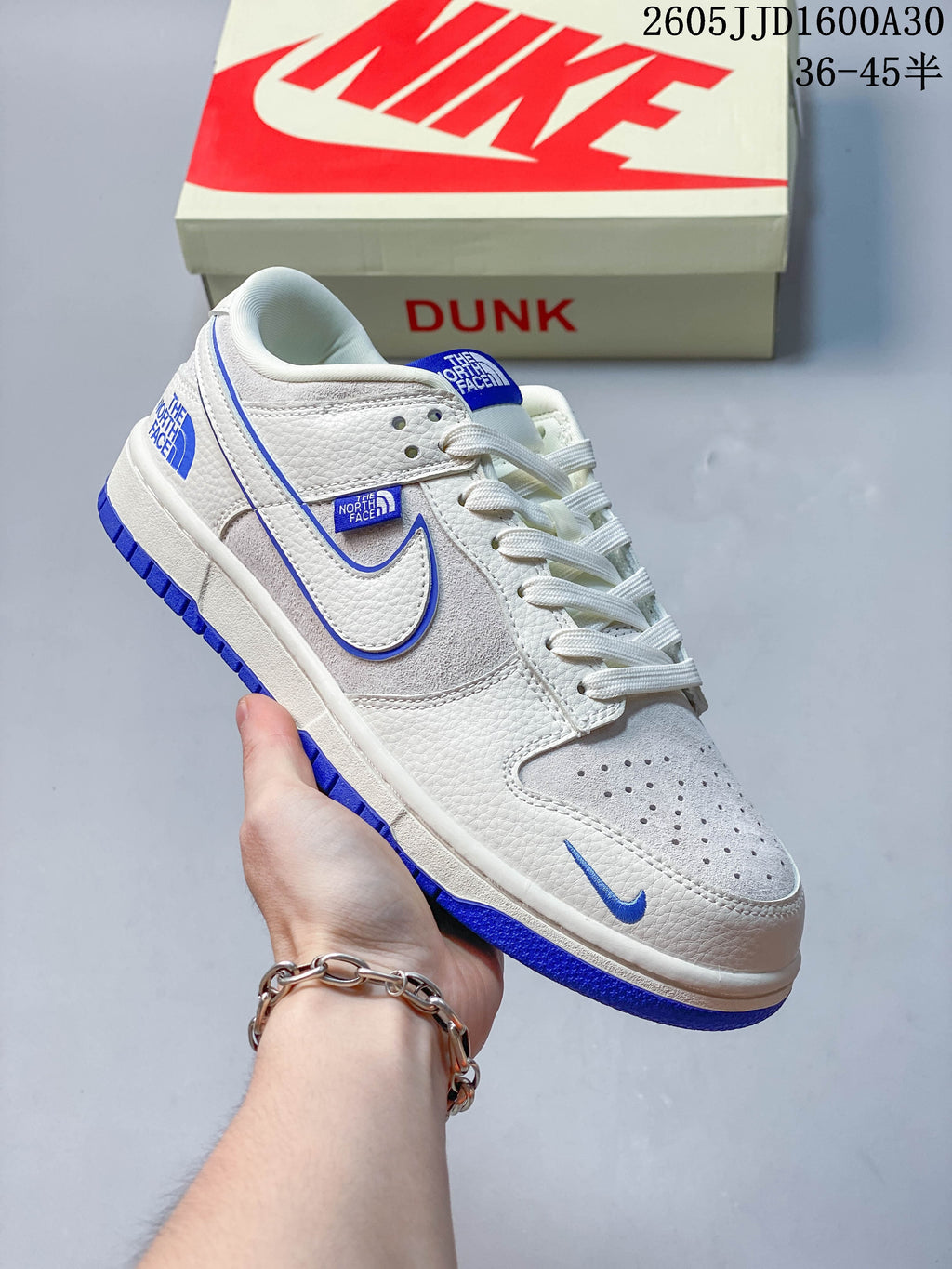 White low-top sneaker with blue details and a Dunk shoe box in the background