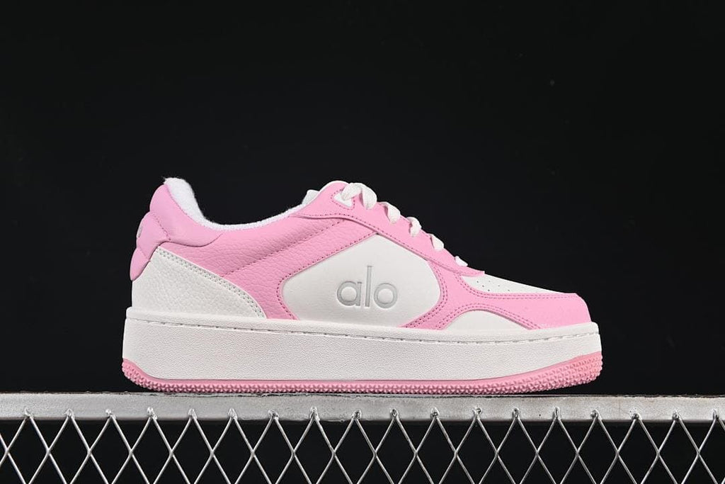 Side profile of a pink and white Alo low-top sneaker with a raised sole