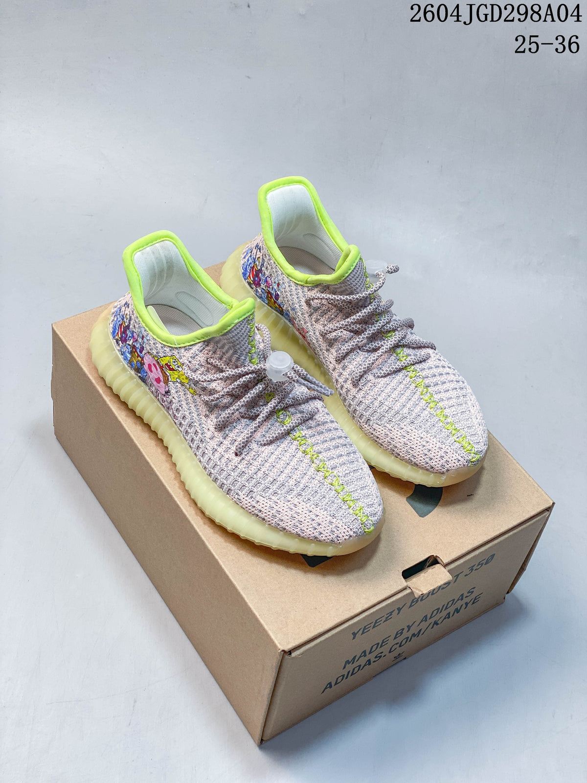 Pair of pale knit-look Adidas Yeezy 350 V2-style kids sneakers with cartoon graphics, lime-green trim, and translucent pale-yellow soles.