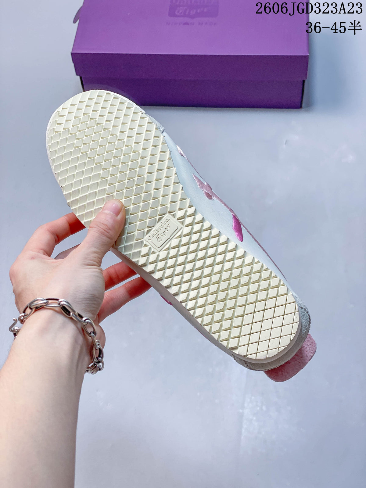 Close-up of the cream patterned outsole and pink heel accent.