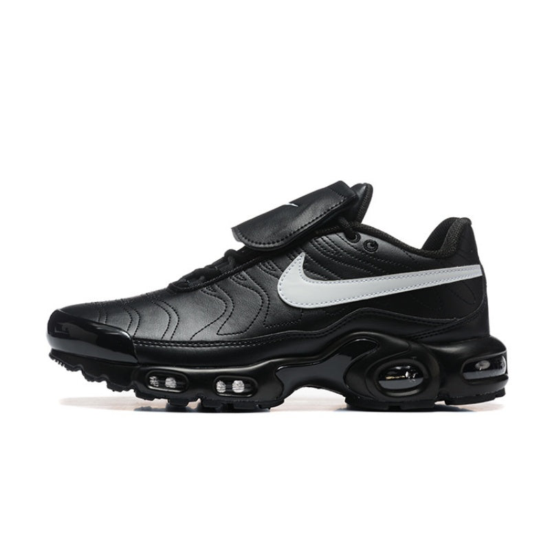 Black Nike Air Max Plus sneaker with a white swoosh and strap across the upper.