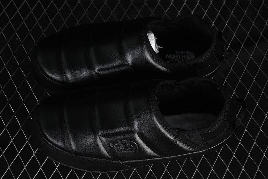 Pair of black slip-on mules viewed from above.