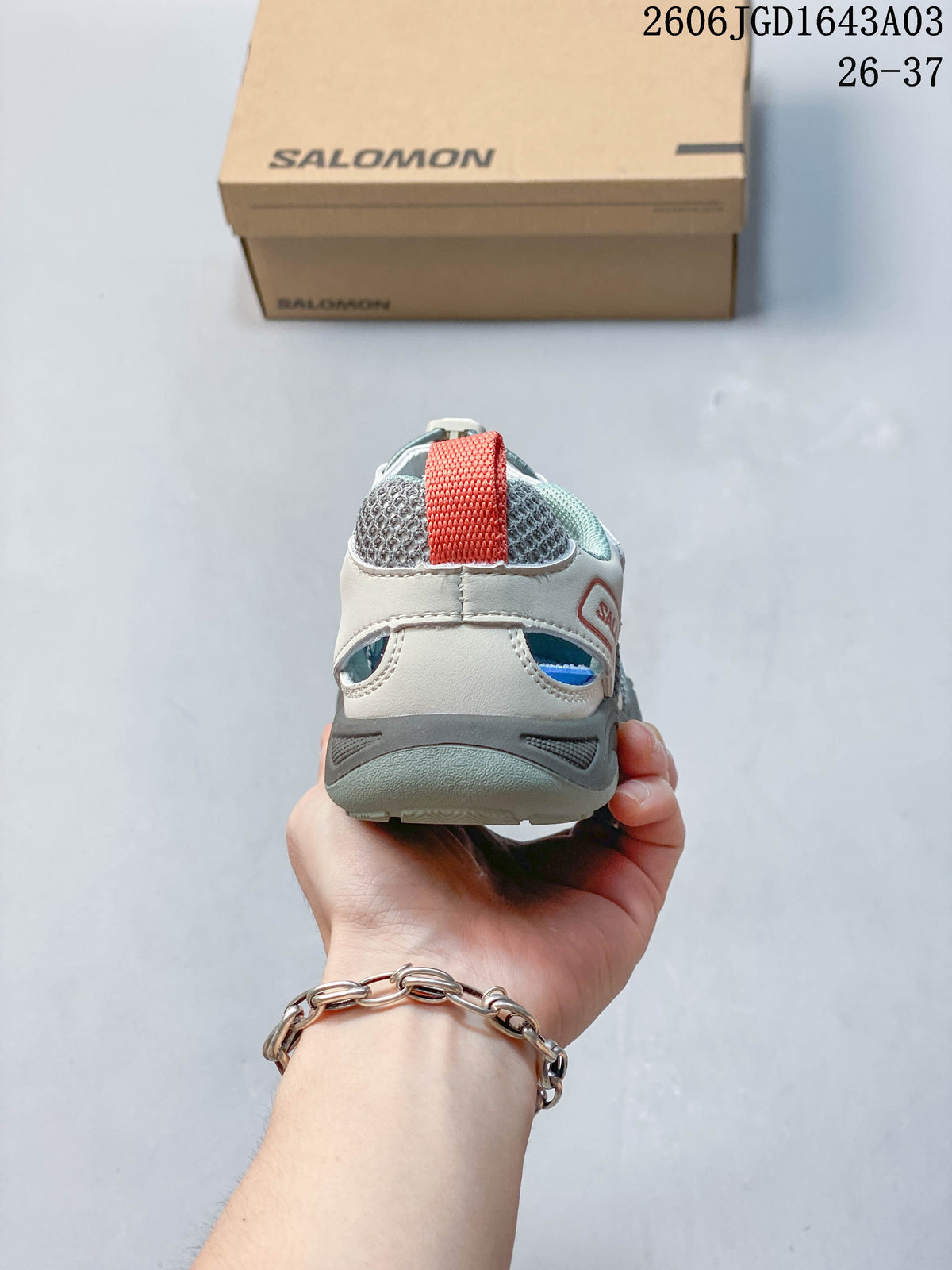 Rear view showing the heel pull tab and gray outsole of a Salomon kids’ sneaker.